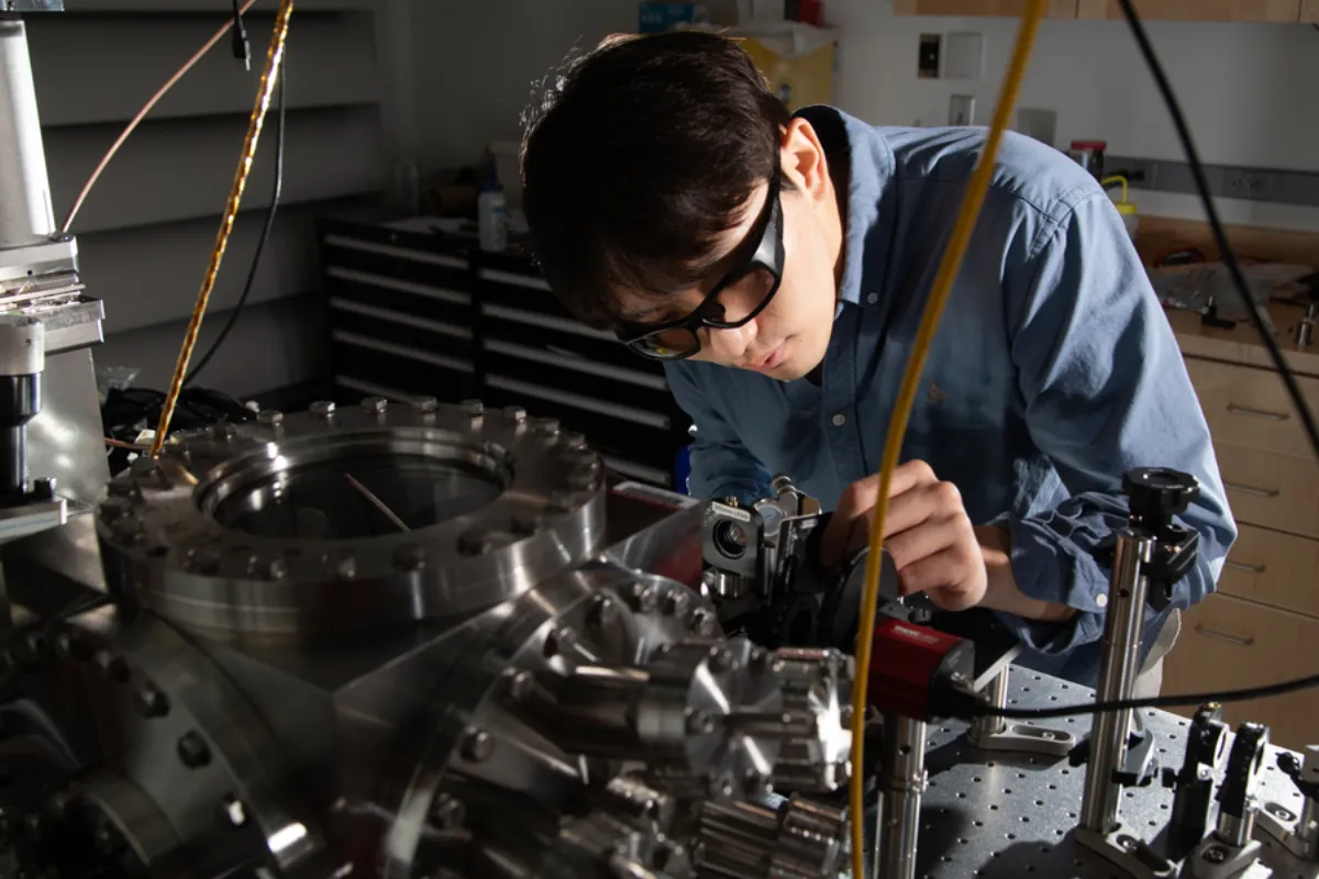 Dongchel Shin aligning optics next to a vacuum chamber in the lab